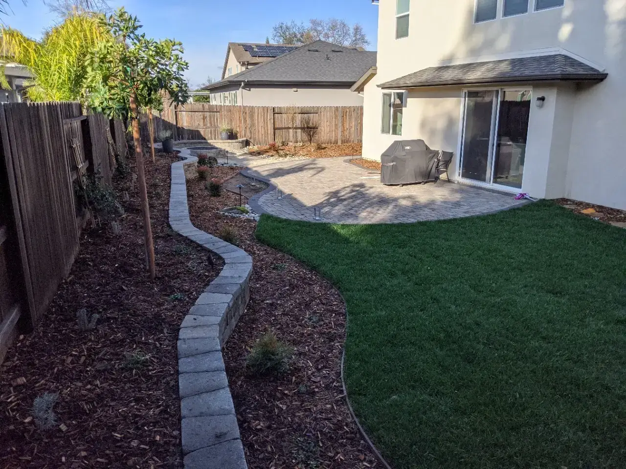 Drought-tolerant backyard redesign with rock bed and shrubs in Citrus Heights, CA