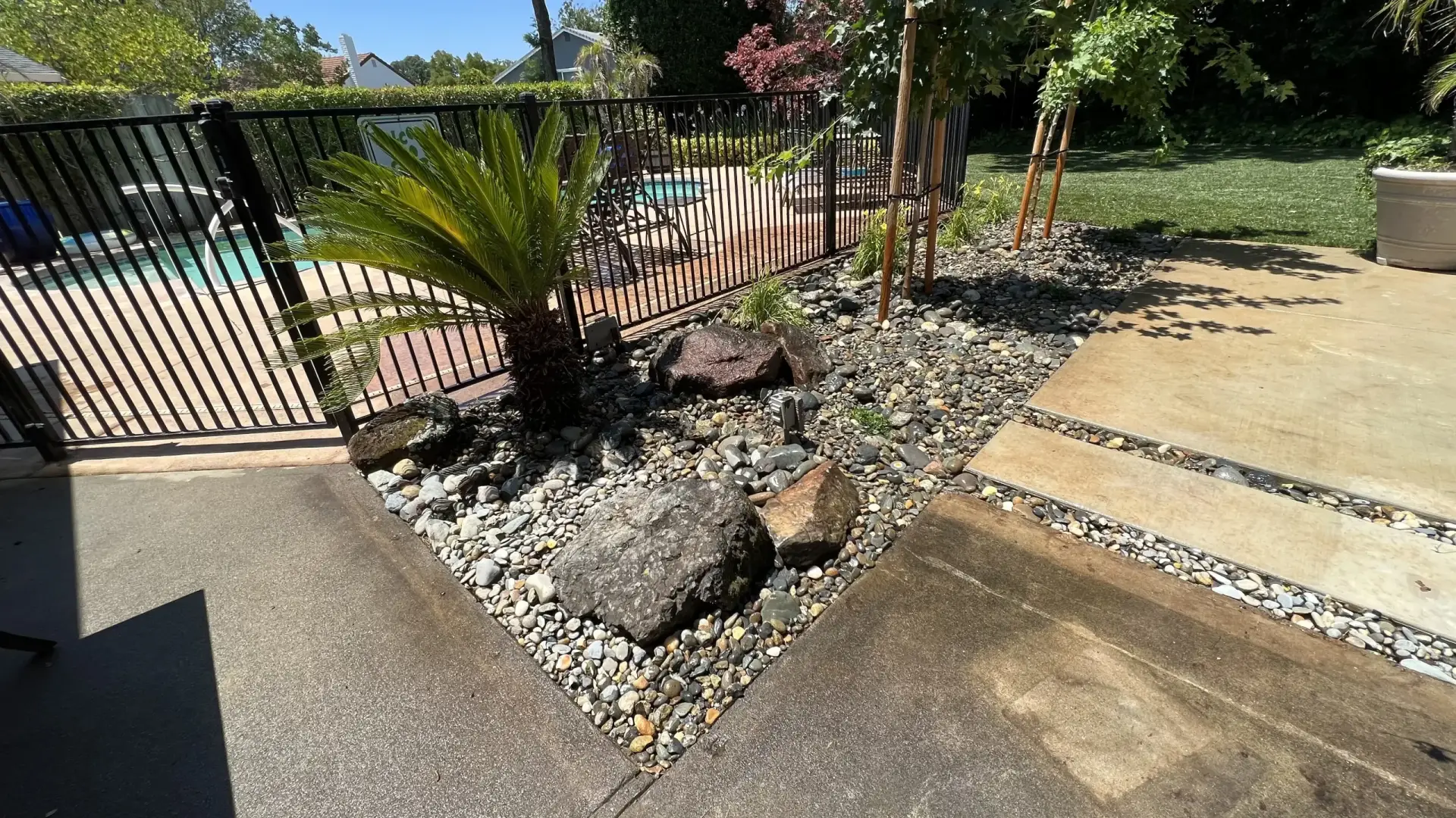 Backyard pool landscape with clean turf and rock work